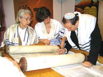 Rabbinical student A. Gegel reads Torah as Faina and Rimma follow along.